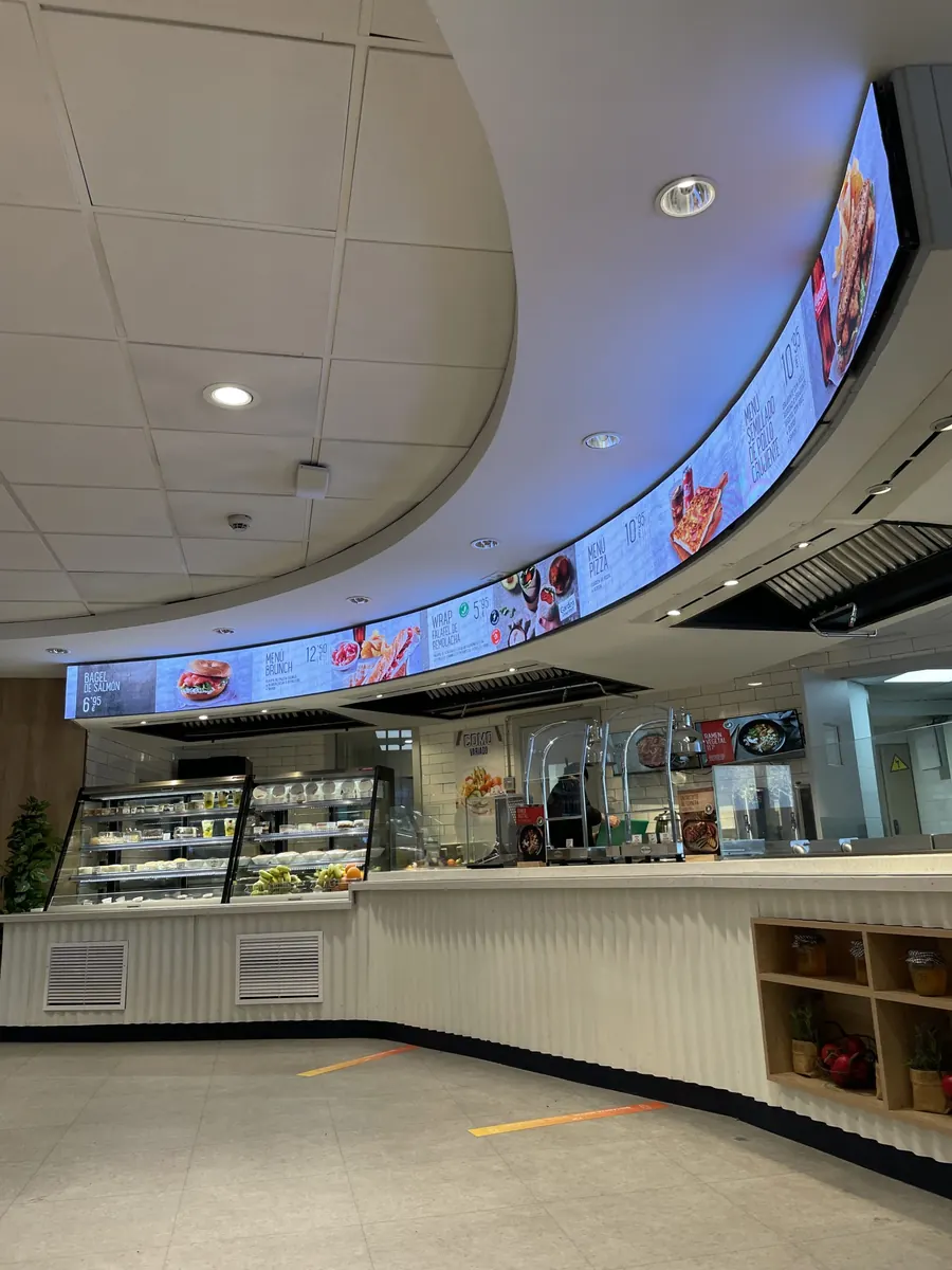 Curved LED screen running along a café counter in Atocha, Madrid