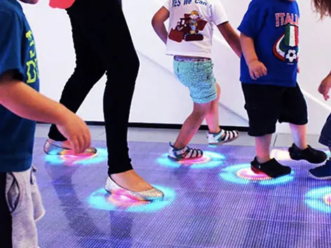 Nens jugant sobre un terra LED interactiu que s'il·lumina sota els seus peus