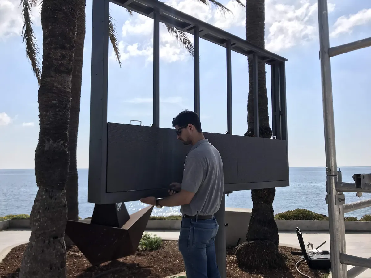 Técnico colocando la pantalla del tótem LED sobre su estructura en el Hotel Atolón