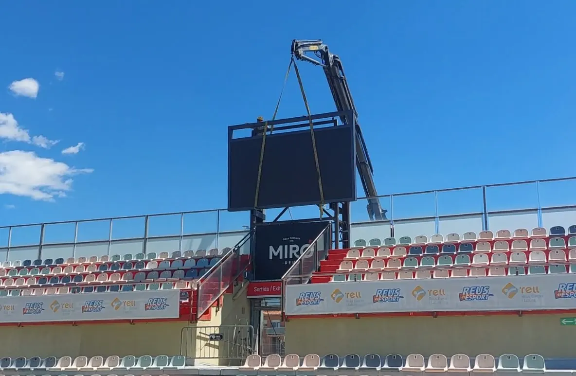Techniciens montant le tableau d'affichage vidéo en haut de la tribune du stade de Reus